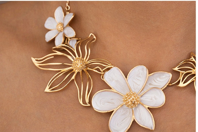 Close-up of handcrafted ethnic necklace showing floral design and white enamel detailing
