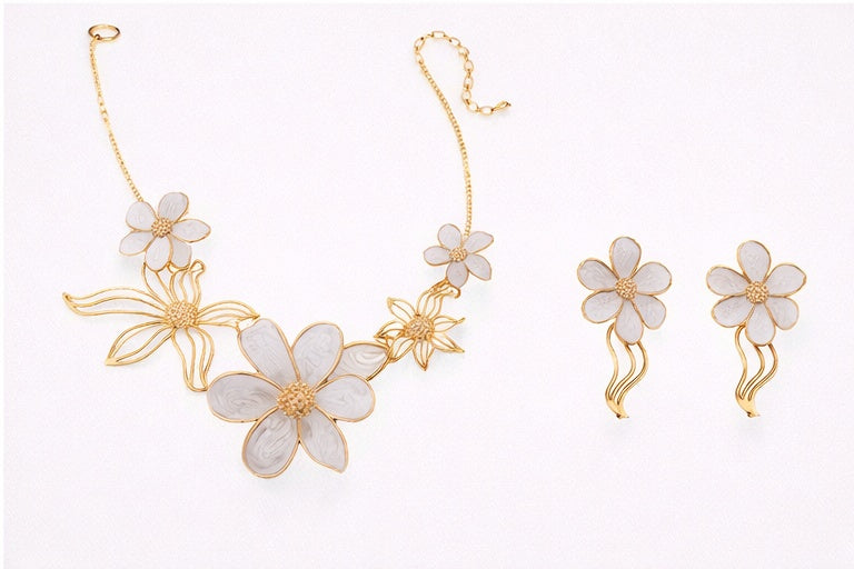Floral jewelry set with gold and white flowers on a light background