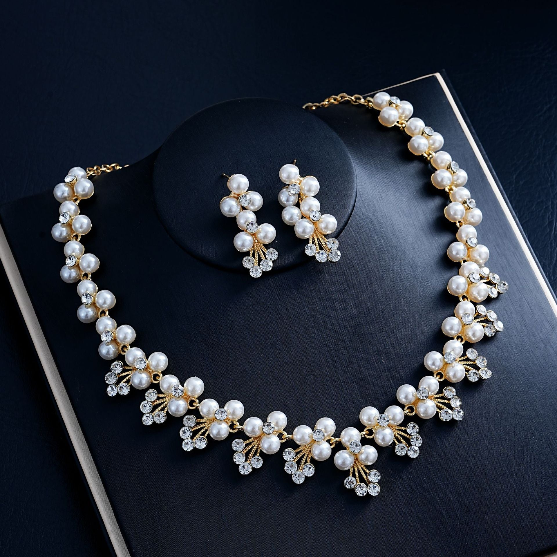 Pearl necklace and earrings on a black surface